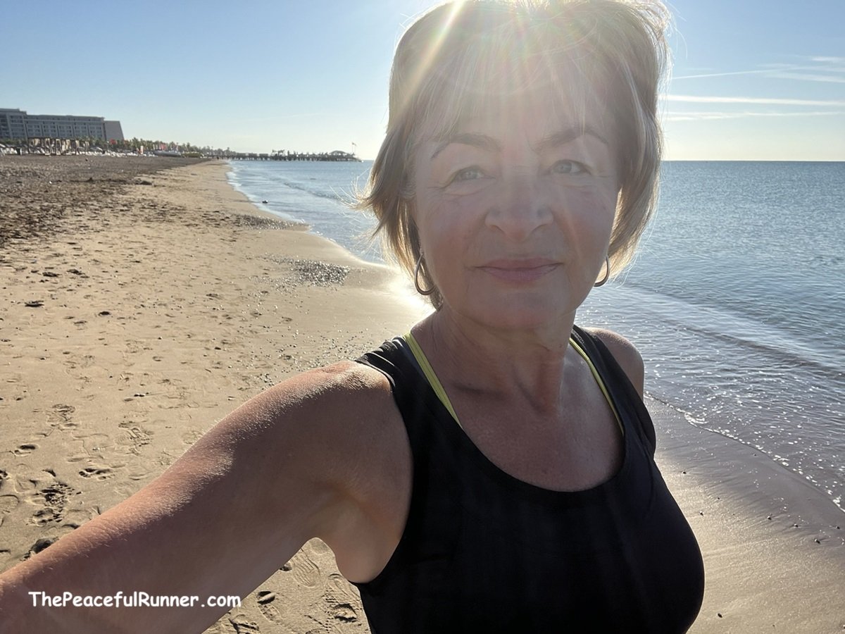 Female runner looking happy on a sandy beach sunny morning